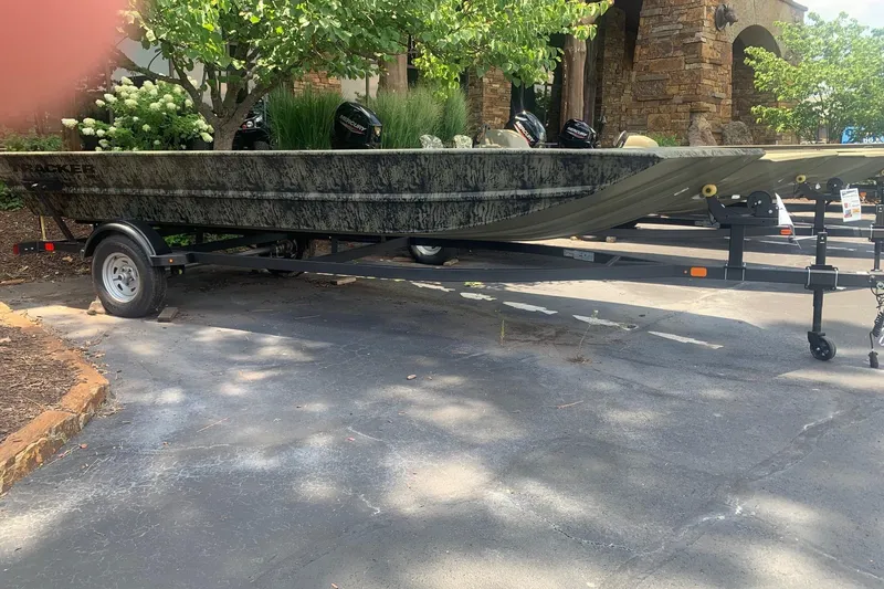 The Image of 2026 Tracker Grizzly 1860 Utility boat on trailer, parked outdoors near trees. - 0