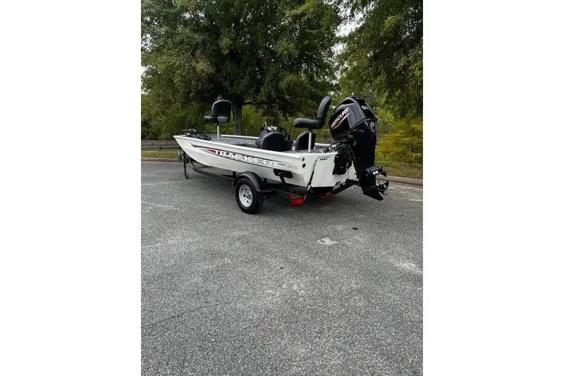 Slide: The Image of 2026 Tracker Pro 170 boat with Mercury engine, parked on asphalt, surrounded by trees. - 2