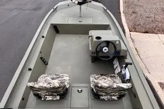 Slide: The Image of 2026 Tracker Grizzly 1754 SC boat interior with camo seats and steering console. - 2