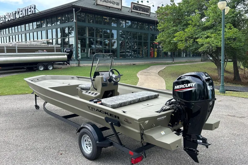 Slide: The Image of 2026 Tracker Grizzly 1860 CC boat with Mercury engine, parked outside a boat center. - 62