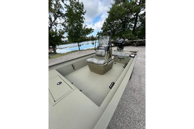 Slide: The Image of 2026 Tracker Grizzly 1860 CC boat with camouflage seating, parked near a lake. - 67