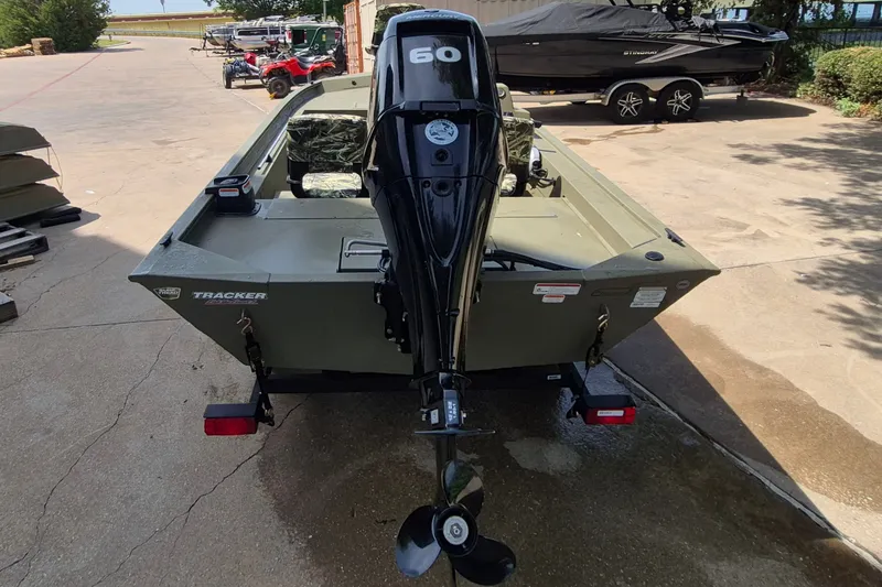Slide: The Image of 2026 Tracker Grizzly 1754 SC boat with 60 HP outboard motor, parked outdoors. - 5