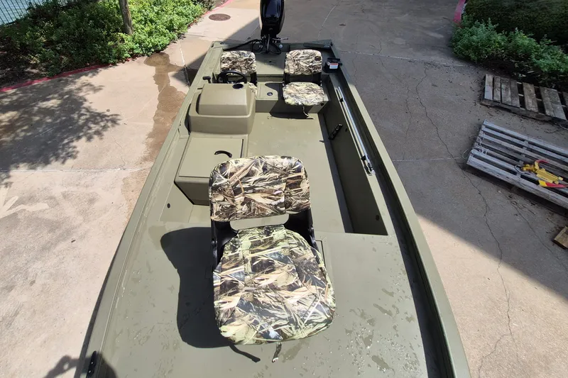 Slide: The Image of 2026 Tracker Grizzly 1754 SC boat with camouflage seats, parked on concrete. - 9