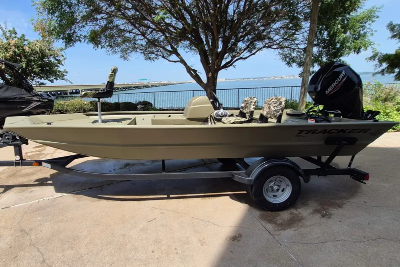The Image of 2026 Tracker Grizzly 1754 SC boat on trailer by lakeside, featuring Mercury engine. - 0