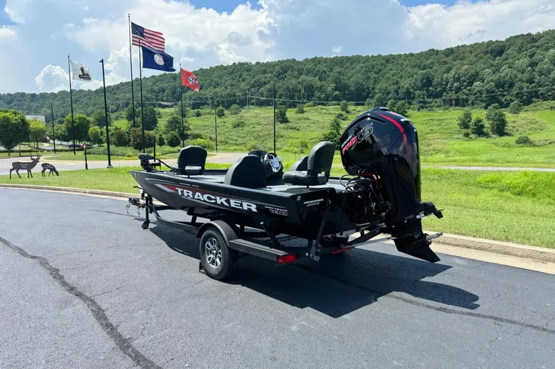 Slide: The Image of 2026 Tracker Pro Team 190 boat on trailer, parked near flags and green landscape. - 4