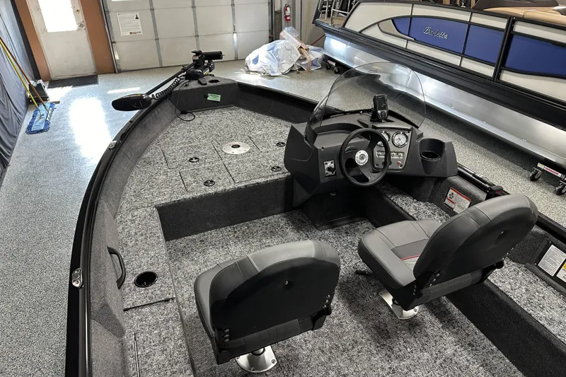 Slide: The Image of 2026 Tracker Pro Guide V-16 SC boat interior with steering console and seating in a garage. - 14