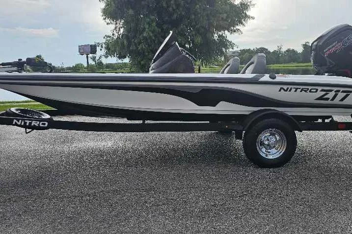 The Image of 2026 Nitro Z17 boat on trailer, parked on asphalt, with trees in the background. - 0