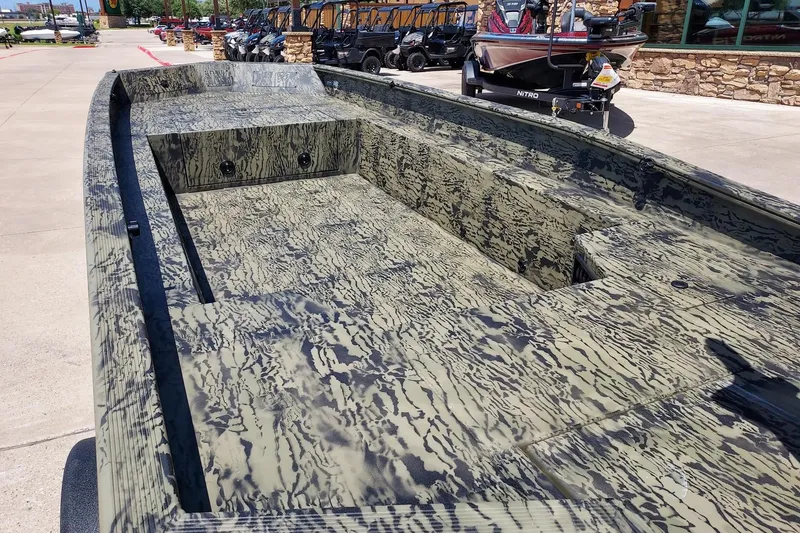 Slide: The Image of 2026 Tracker Grizzly 1650 T Prairie Wings Edition boat with camouflage design, parked outdoors. - 2