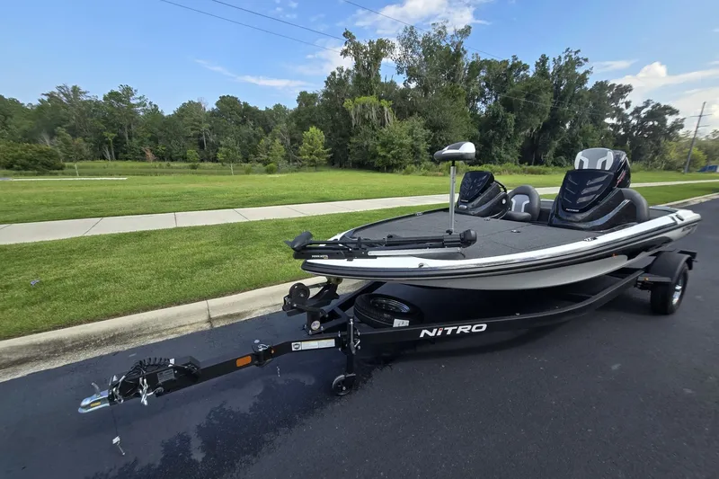 Slide: The Image of 2026 Nitro Z17 boat on trailer, parked on road with lush greenery background. - 6