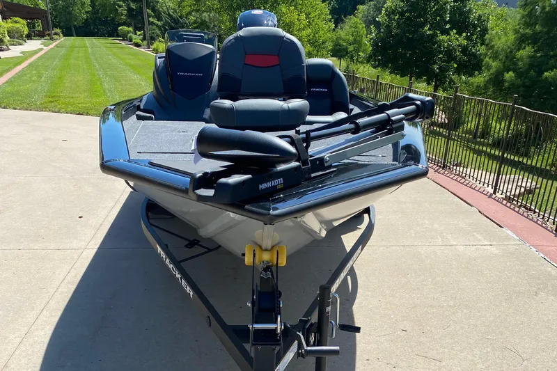 Slide: The Image of 2026 Tracker Pro Team 190 boat on trailer, parked on driveway, surrounded by greenery. - 2