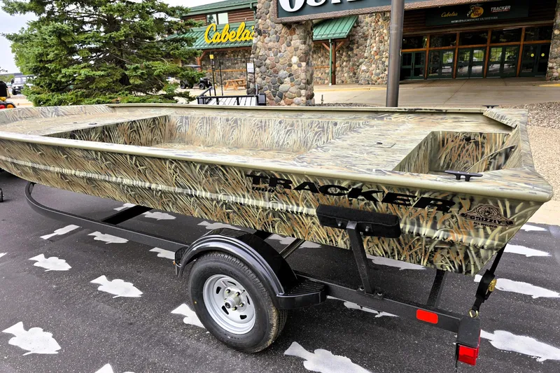 Slide: The Image of 2026 Tracker GRIZZLY 1860 Utility boat with camouflage design on a trailer outside Cabela's store. - 3