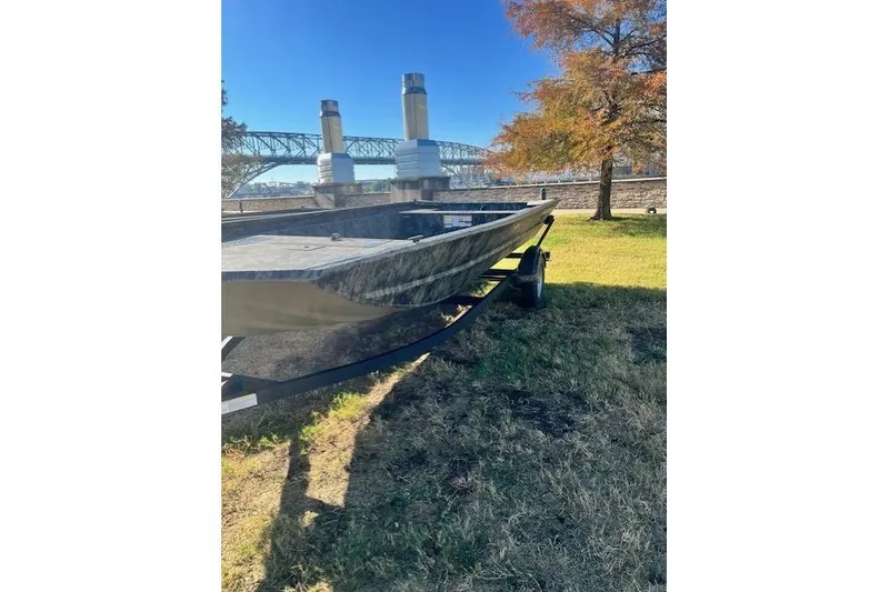 Slide: The Image of 2026 Tracker Grizzly 1860 Utility boat on grass near a bridge and autumn tree. - 18