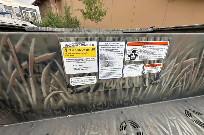 Slide: The Image of 2026 Tracker Grizzly 1648 Utility boat safety and capacity warning labels. - 16