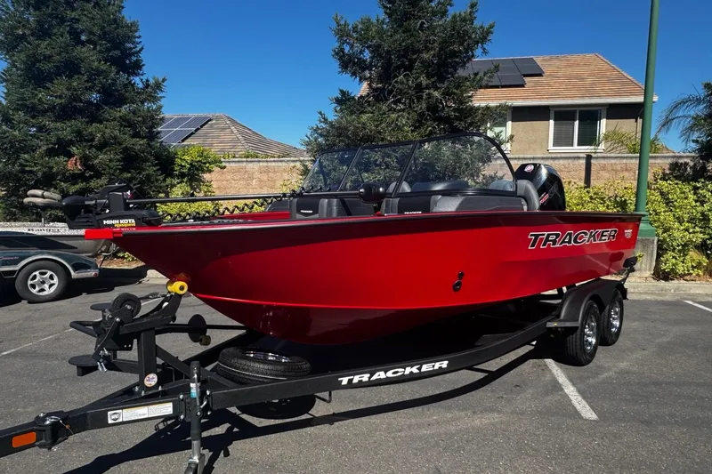 Slide: The Image of 2026 Tracker Targa V-18 WT boat in vibrant red on a trailer, parked outdoors. - 2