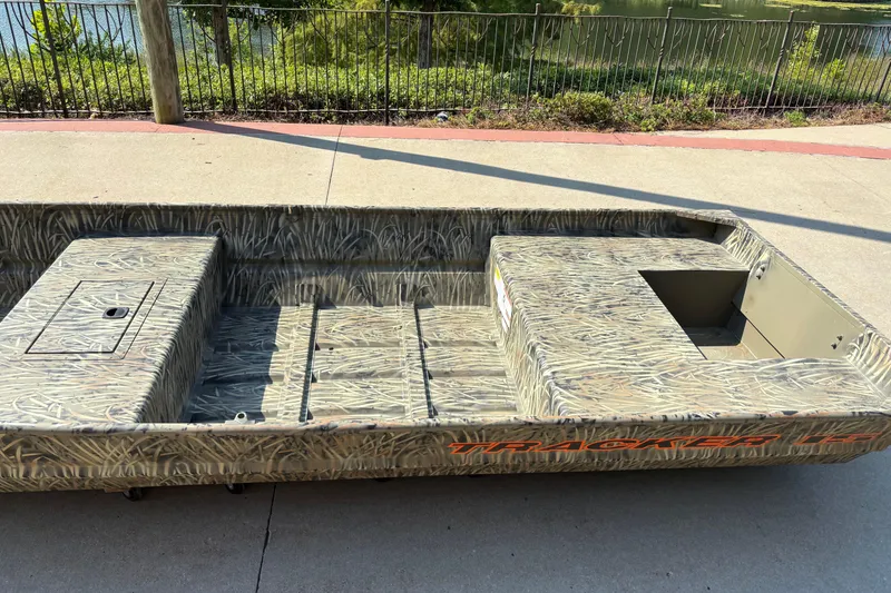 Slide: The Image of 2026 Tracker Grizzly 15 Jon boat with camouflage design on a concrete surface. - 2