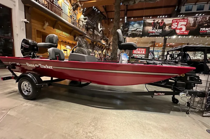 Slide: The Image of 2026 Tracker Bass Tracker Classic XL boat displayed indoors, featuring a sleek red design. - 2