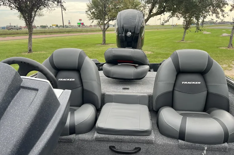 Slide: The Image of 2026 Tracker Pro Team 175 boat interior with gray seating and motor, parked on grass. - 5