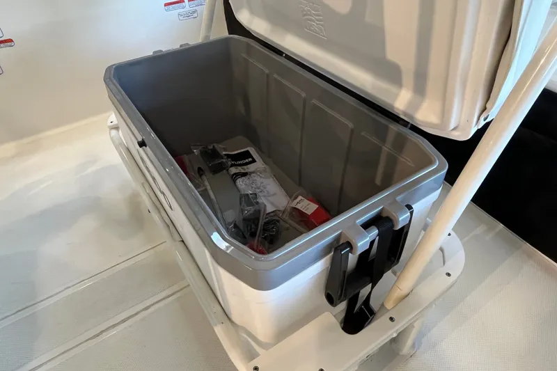 Slide: The Image of Open storage compartment on 2026 Mako Pro Skiff 17 CC boat, containing various items. - 18