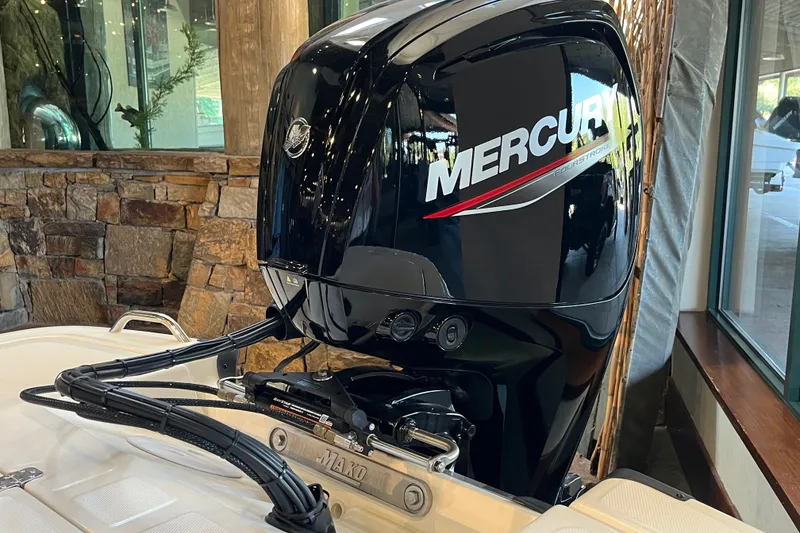 Slide: The Image of 2026 Mako Pro Skiff 17 CC with Mercury outboard motor, displayed indoors. - 22