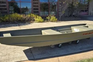 Slide: The Image of 2026 Tracker Grizzly 14 Jon boat displayed outdoors on a sunny day. - 2
