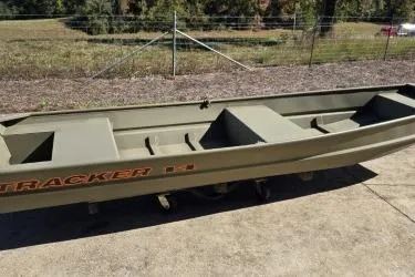 Slide: The Image of 2026 Tracker Grizzly 14 Jon boat on concrete, outdoors, with grassy background. - 5