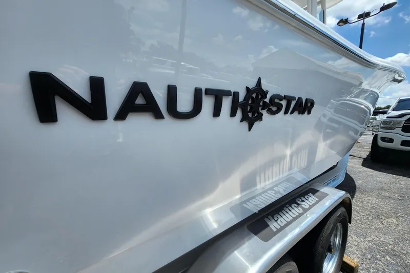 Slide: The Image of 2026 NauticStar 252 Legacy boat side view with logo in a parking lot. - 12