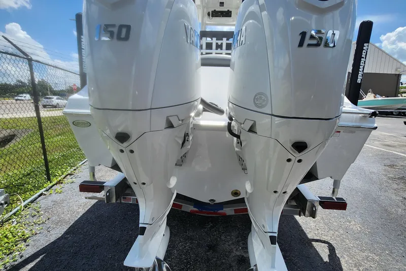 Slide: The Image of 2026 NauticStar 252 Legacy with twin Yamaha 150 outboard engines, parked outdoors. - 2
