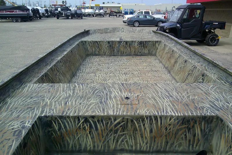 Slide: The Image of 2026 Tracker Grizzly 1860 Utility boat with camouflage design in a dealership lot. - 3