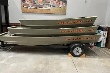 The Image of 2026 Tracker Grizzly 12 Jon boats stacked on a trailer in a showroom. - 0