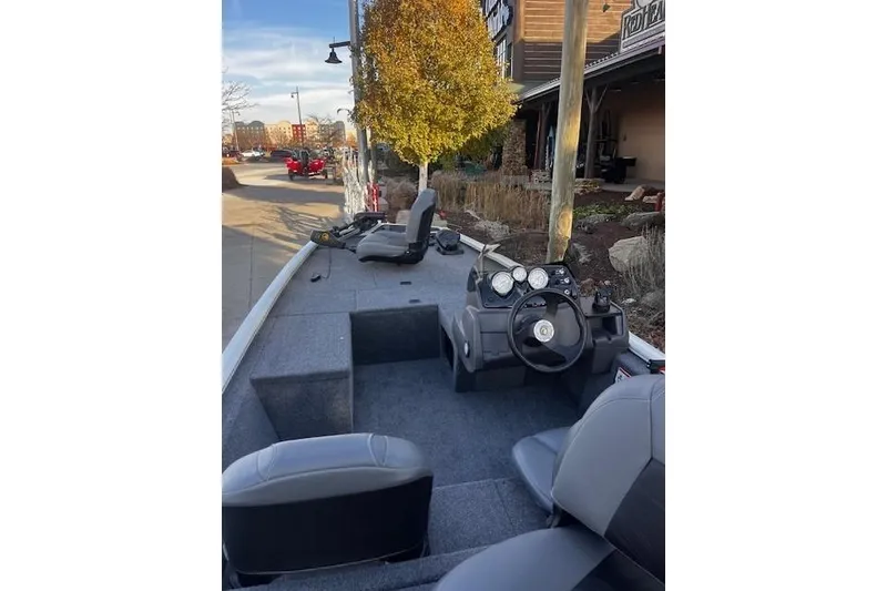 Slide: The Image of 2026 Tracker Pro 170 boat interior with steering wheel and seating, parked outdoors. - 63