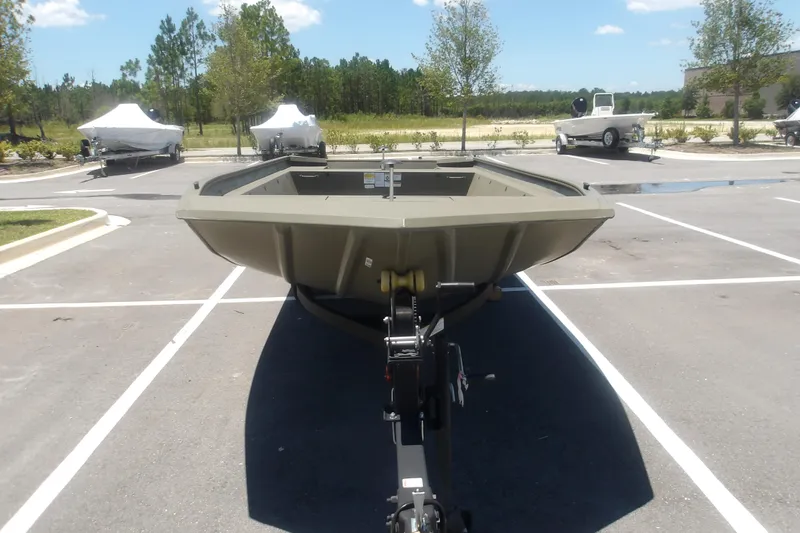 Slide: The Image of 2026 Tracker Grizzly 1860 Utility boat in parking lot, surrounded by trees and other boats. - 14