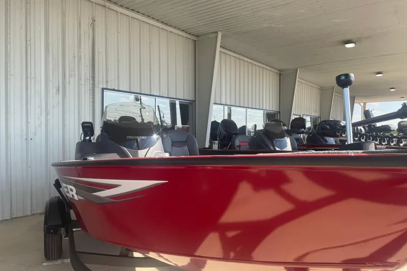 Slide: The Image of 2026 Tracker Super Guide V-16 SC boat in vibrant red, parked under a metal canopy. - 4