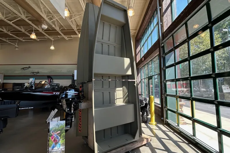 Slide: The Image of 2026 Tracker Grizzly 12 Jon boat displayed in a showroom with large windows. - 2