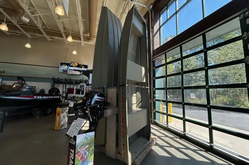 Slide: The Image of 2026 Tracker Grizzly 12 Jon boat displayed in a showroom with Mercury engines. - 3