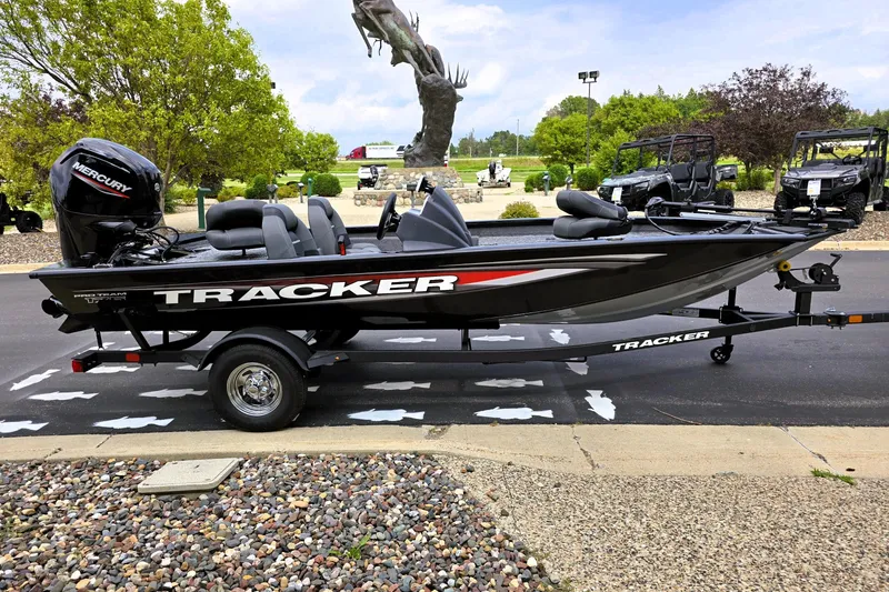 Slide: The Image of 2026 Tracker Pro Team 175 boat on trailer, parked outdoors with trees in background. - 5