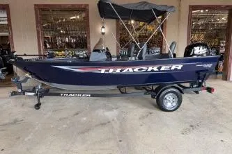 Slide: The Image of 2026 Tracker Pro Guide V-16 SC boat with canopy on trailer, parked indoors. - 4