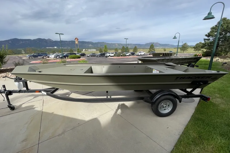 The Image of 2026 Tracker Grizzly 1860 Utility boat on trailer, parked outdoors with scenic mountain backdrop. - 0