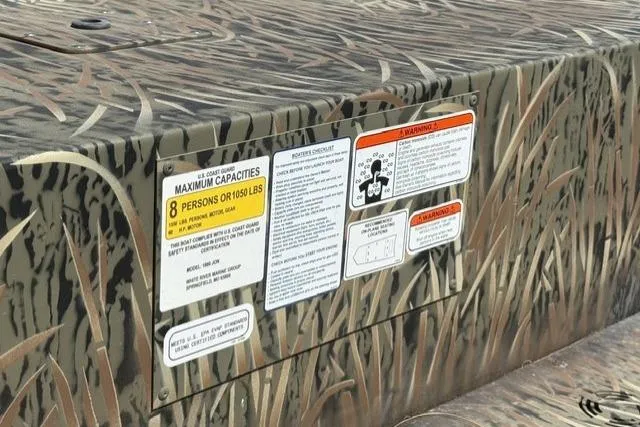 Slide: The Image of 2026 Tracker Grizzly 1860 Utility boat with camouflage design and capacity warning labels. - 6