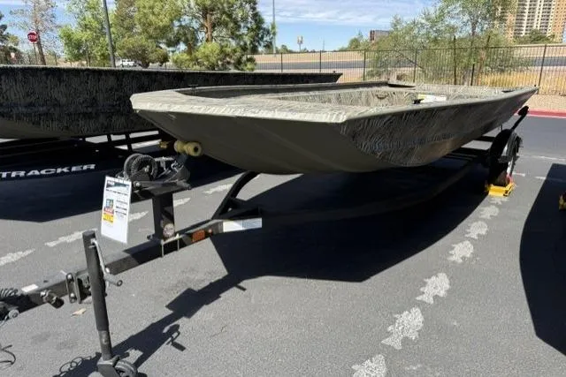 Slide: The Image of 2026 Tracker Grizzly 1860 Utility boat on trailer, parked outdoors in a sunny setting. - 2