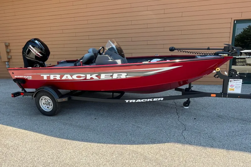The Image of Red 2026 Tracker Super Guide V-16 SC boat on trailer, parked outdoors. - 0