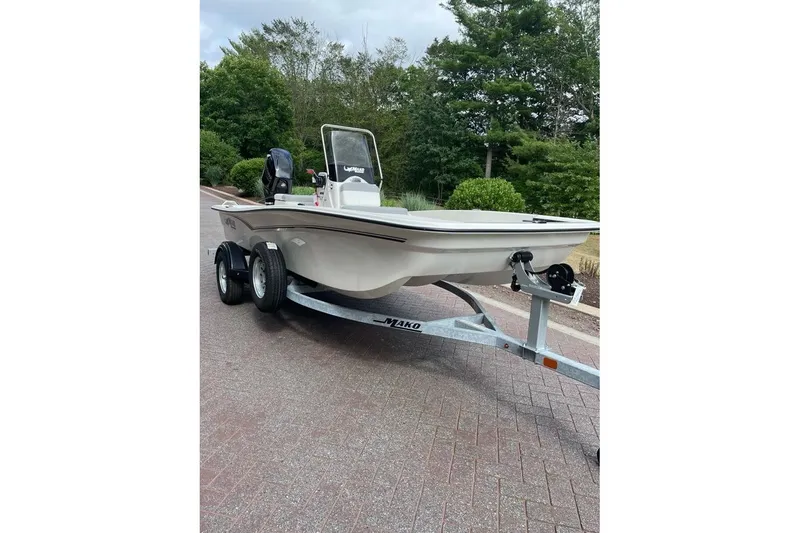 Slide: The Image of 2026 Mako Pro Skiff 15 CC boat on trailer, parked on a paved road. - 2