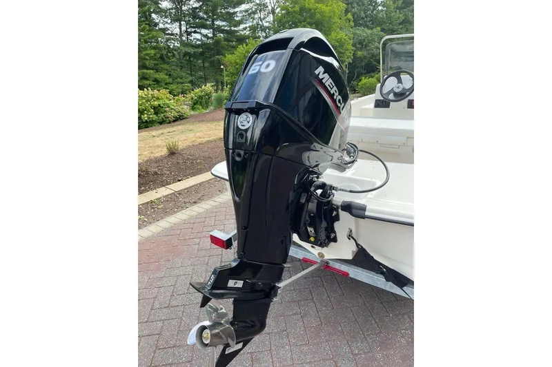 Slide: The Image of 2026 Mako Pro Skiff 15 CC with Mercury outboard motor, parked on a brick driveway. - 4