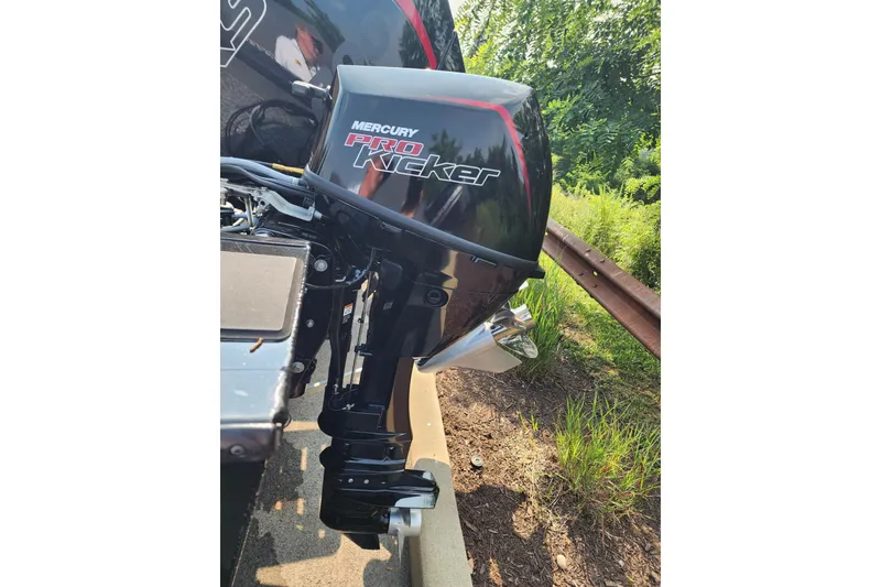 Slide: The Image of Mercury Pro Kicker motor on 2026 Tracker Targa V-18 WT boat, parked near greenery. - 5