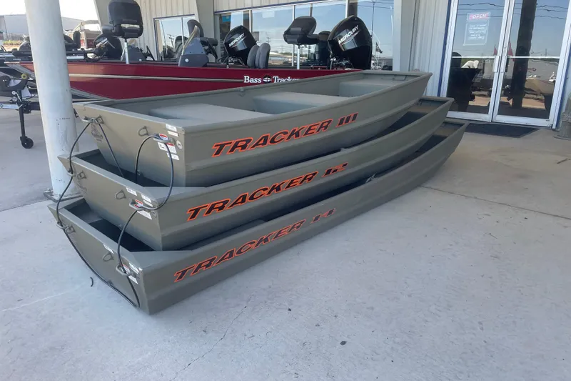 Slide: The Image of Stacked 2026 Tracker Grizzly 10 Jon boats displayed outside a dealership. - 2