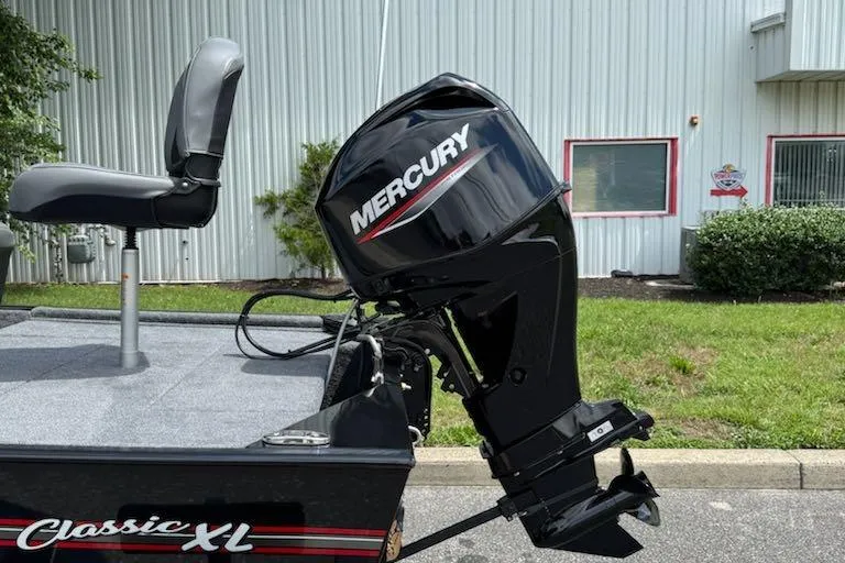 Slide: The Image of 2026 Tracker Bass Tracker Classic XL with Mercury outboard motor, parked near a building. - 3
