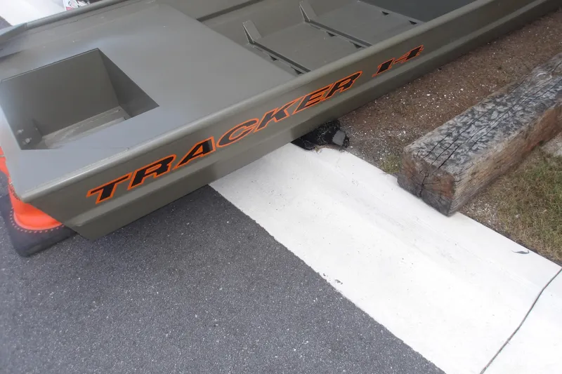 The Image of 2026 Tracker Grizzly 14 Jon boat on pavement near wooden beam. - 0