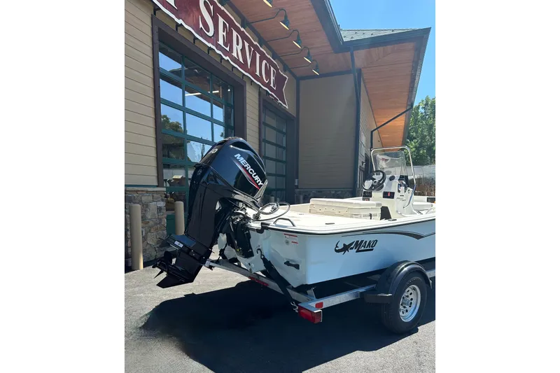 Slide: The Image of 2026 Mako Pro Skiff 17 CC boat with Mercury engine outside service center. - 2