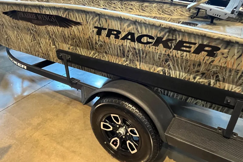 Slide: The Image of 2026 Tracker Grizzly 1650 T Prairie Wings Edition boat with camouflage design and black trailer. - 3