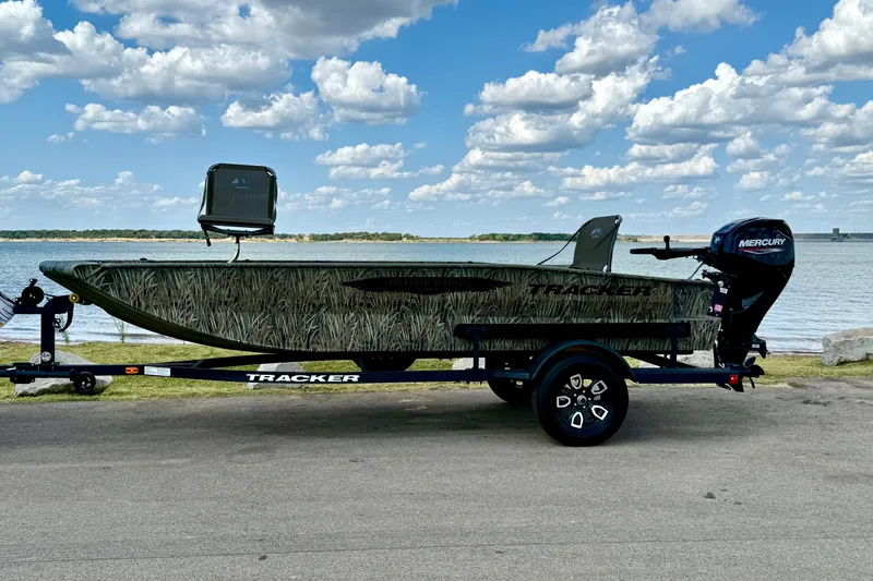 Slide: The Image of 2026 Tracker Grizzly 1650 T Prairie Wings Edition boat by a lake under a cloudy sky. - 13