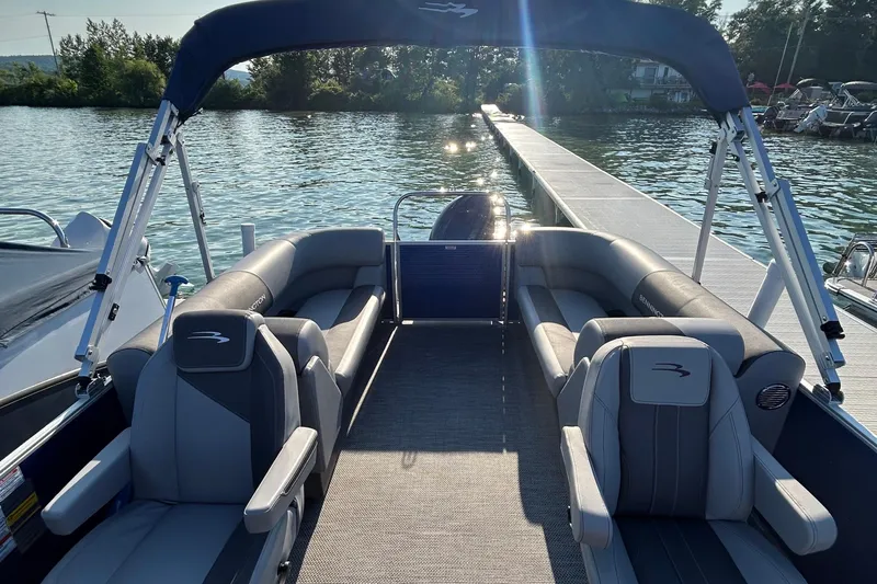 Slide: The Image of 2024 Bennington 22 SSR pontoon boat interior with plush seating, docked on a sunny lake. - 3